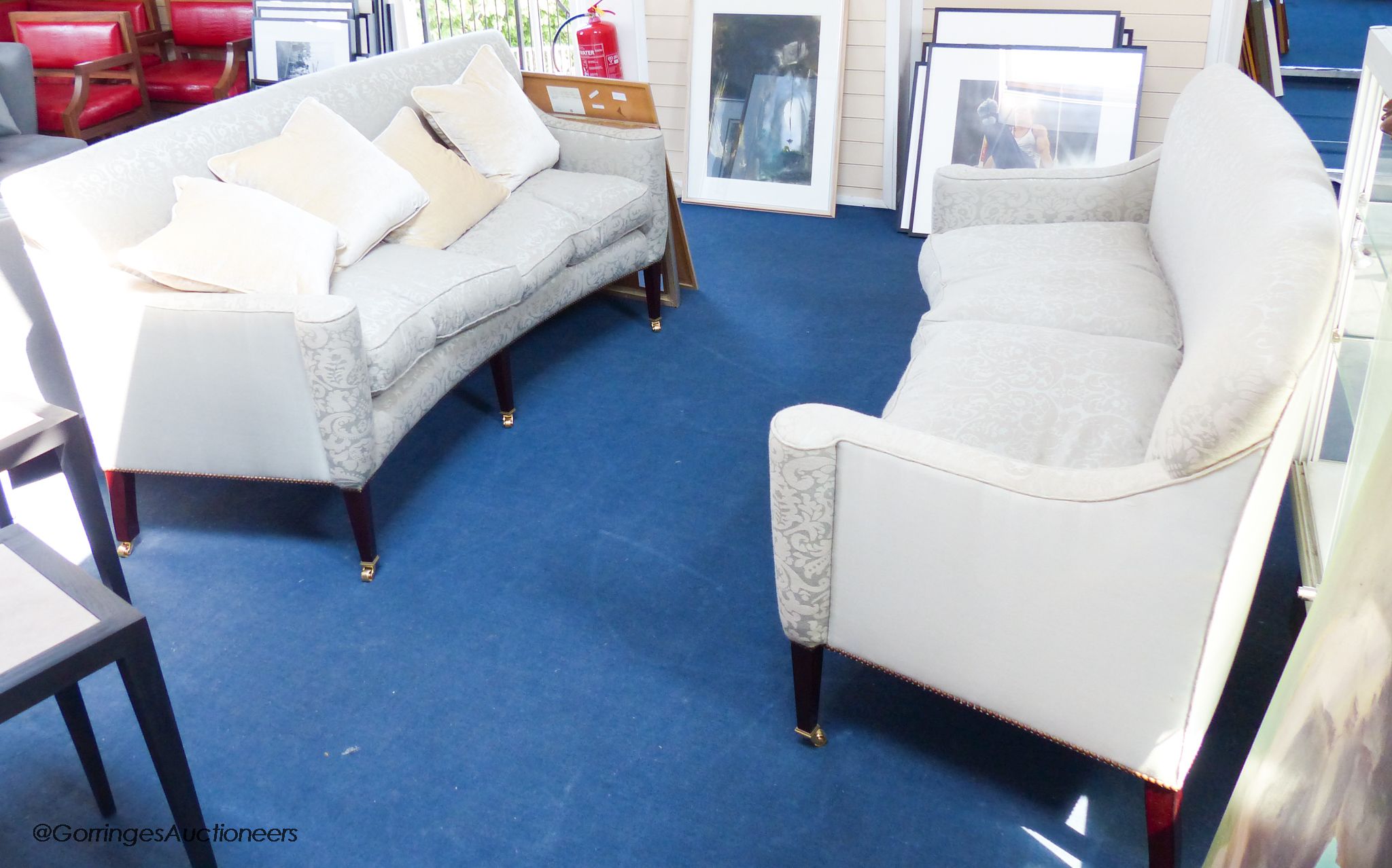 A pair of George III style eau de nil silk damask concave fronted two seat sofas, on square tapered mahogany legs with brass casters, approximately 188 cm wide